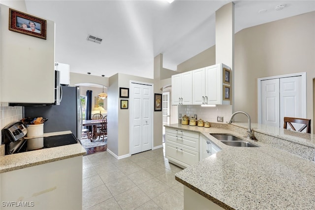 kitchen with sink, white cabinets, decorative backsplash, and lofted ceiling