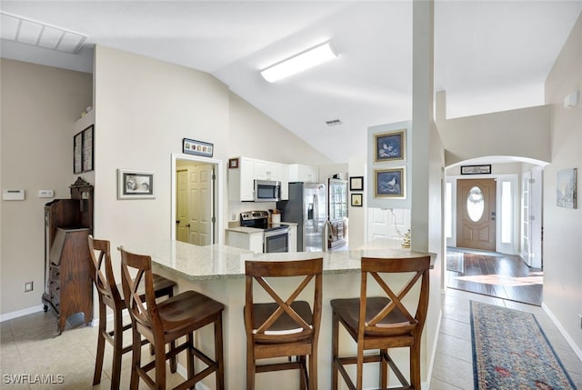 kitchen featuring a breakfast bar, kitchen peninsula, white cabinets, and stainless steel appliances