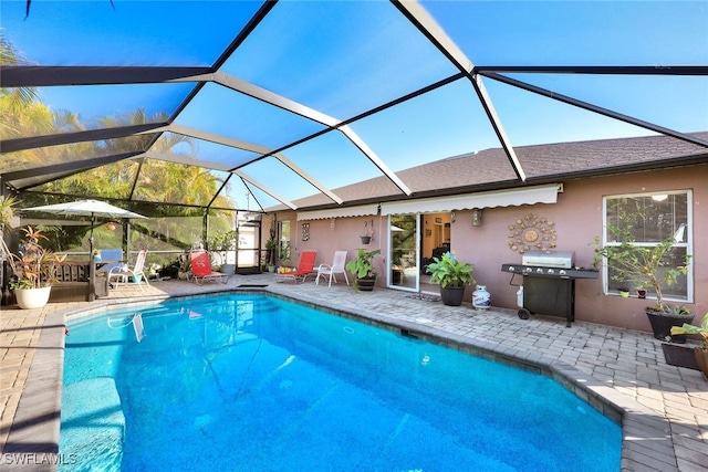 view of pool with a patio, glass enclosure, and a grill