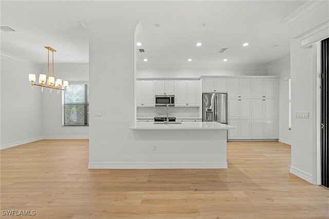 kitchen featuring crown molding, white cabinets, tasteful backsplash, and stainless steel appliances