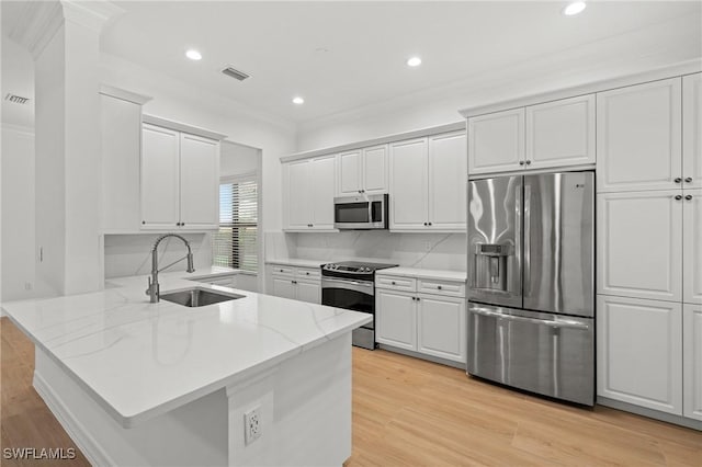 kitchen with a peninsula, light wood-style flooring, appliances with stainless steel finishes, and a sink