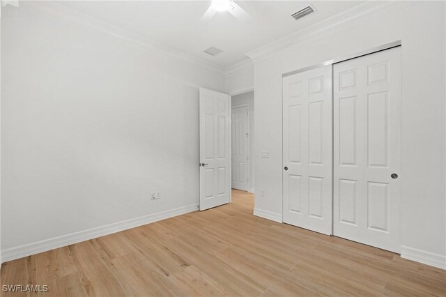 unfurnished bedroom featuring ceiling fan, a closet, ornamental molding, and light wood-type flooring