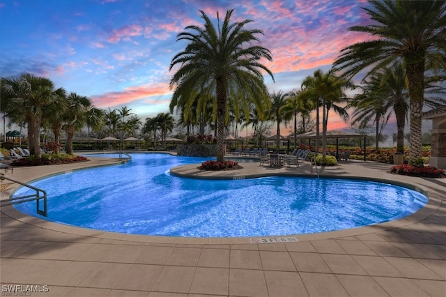 pool at dusk featuring a patio