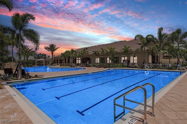 pool at dusk featuring a patio