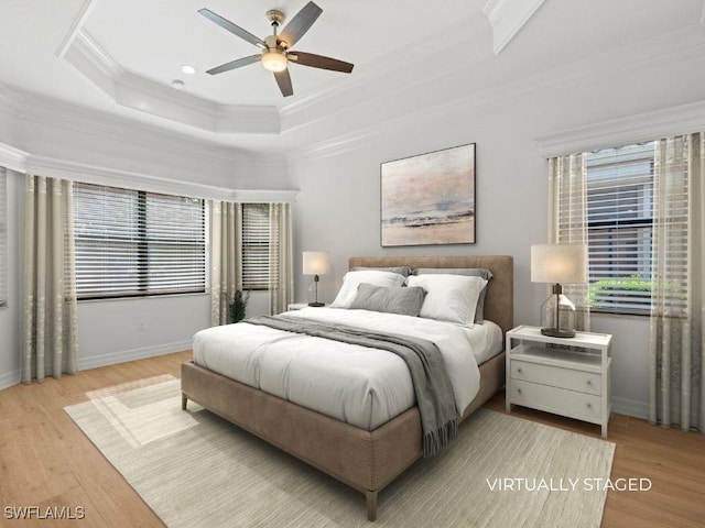 bedroom with a tray ceiling, ornamental molding, ceiling fan, wood finished floors, and baseboards