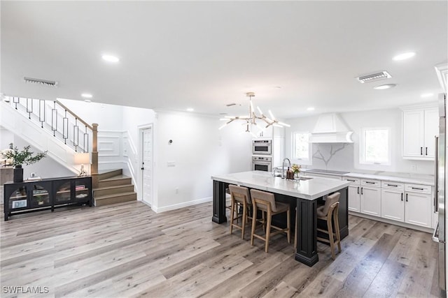 kitchen with pendant lighting, light hardwood / wood-style flooring, a breakfast bar, a center island, and white cabinets