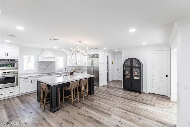 kitchen with sink, a kitchen island with sink, hanging light fixtures, a kitchen breakfast bar, and stainless steel appliances