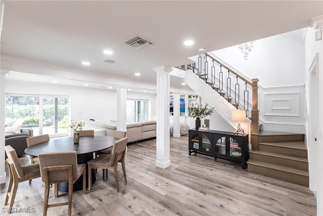 dining space with decorative columns, crown molding, plenty of natural light, and light hardwood / wood-style floors