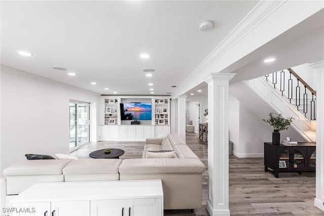 living room with decorative columns, crown molding, light wood-type flooring, and built in shelves