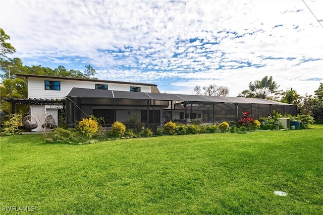 back of property with a pergola, a yard, and glass enclosure