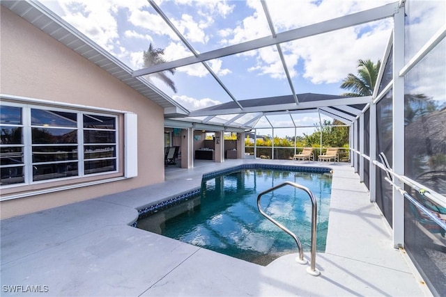 view of pool with glass enclosure and a patio area