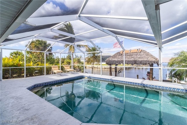 view of swimming pool featuring a water view, a patio area, and glass enclosure