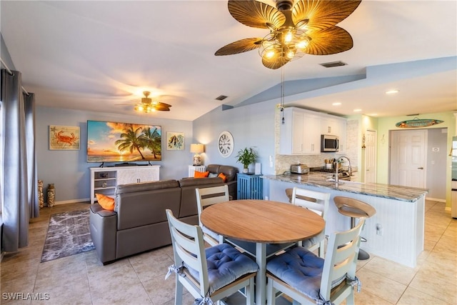 tiled dining room with ceiling fan, lofted ceiling, and sink