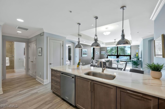 kitchen featuring a sink, dishwasher, ornamental molding, open floor plan, and pendant lighting