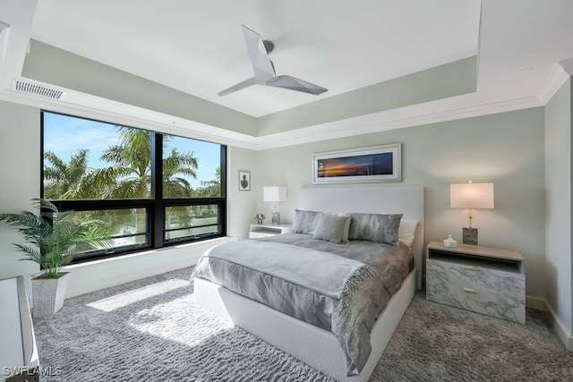 carpeted bedroom featuring a tray ceiling, crown molding, a ceiling fan, and baseboards