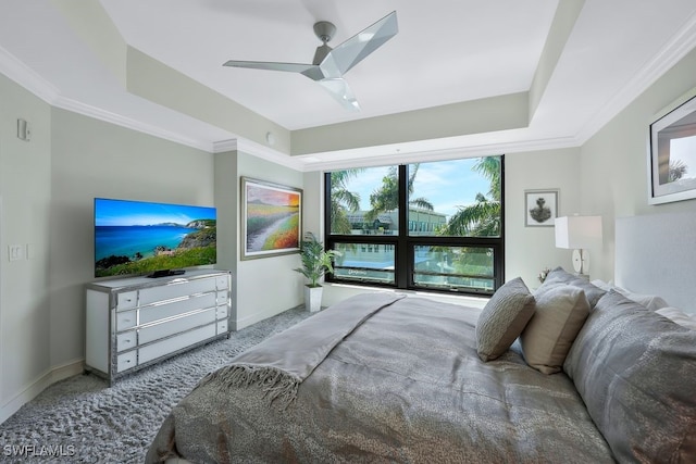 carpeted bedroom with baseboards, ceiling fan, a raised ceiling, and crown molding