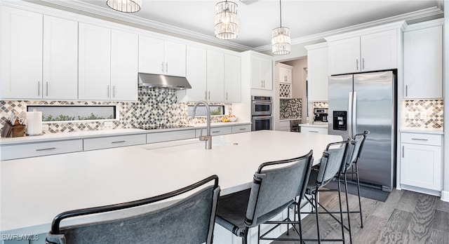 kitchen with appliances with stainless steel finishes, white cabinetry, pendant lighting, dark wood-type flooring, and backsplash