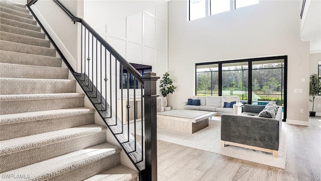 living room with light wood-type flooring and a towering ceiling