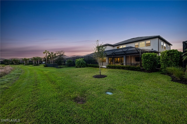 yard at dusk featuring glass enclosure