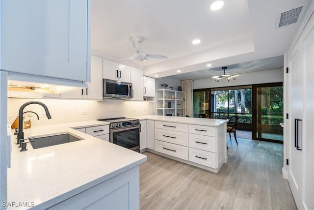 kitchen featuring stainless steel appliances, light countertops, visible vents, white cabinetry, and a peninsula