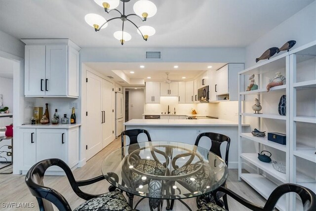 dining area with sink, a notable chandelier, and light hardwood / wood-style flooring