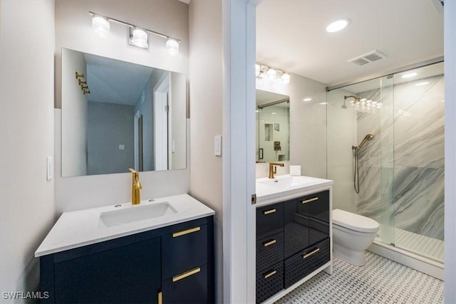 full bath with a marble finish shower, visible vents, two vanities, and a sink