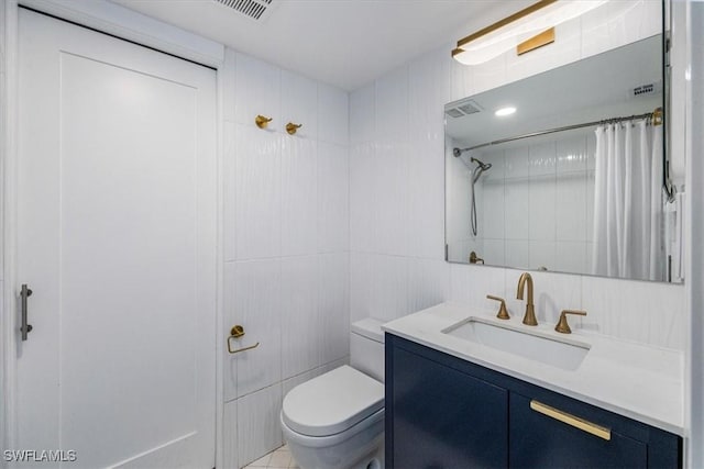 full bathroom with visible vents, tiled shower, toilet, vanity, and tile walls