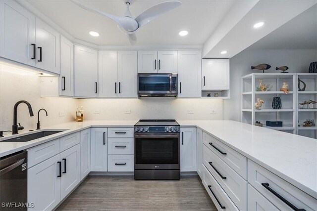 kitchen with stainless steel appliances, white cabinetry, wood-type flooring, and sink