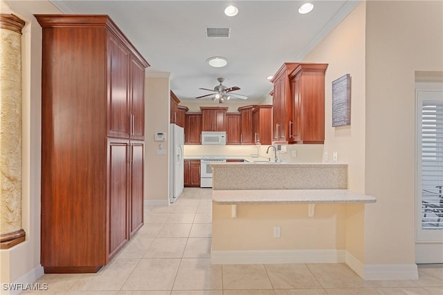 kitchen featuring kitchen peninsula, white appliances, a kitchen bar, and ornamental molding