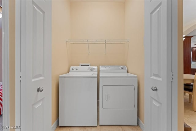 clothes washing area with washer and dryer and light tile patterned floors