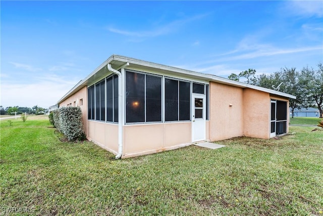 rear view of house featuring a yard and a sunroom