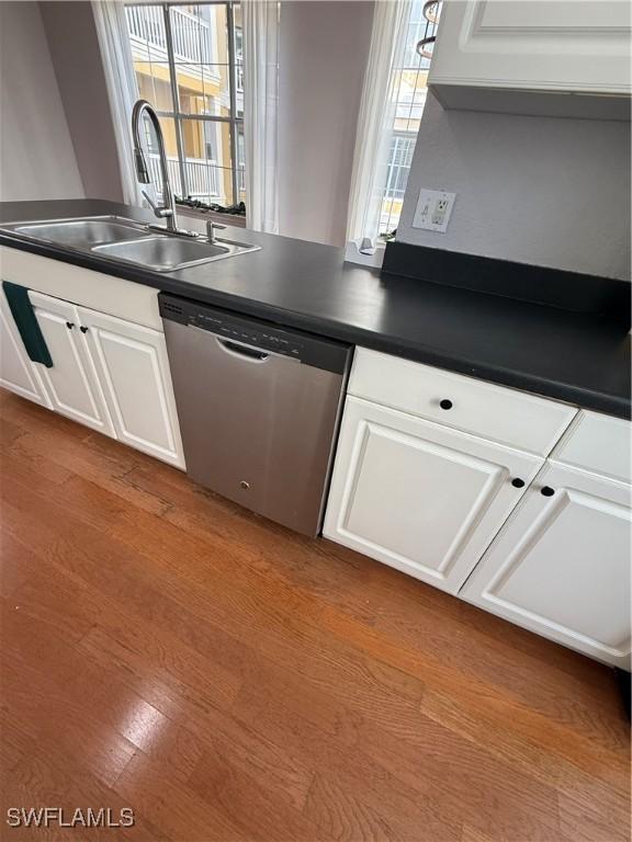 kitchen with white cabinetry, sink, stainless steel dishwasher, and light hardwood / wood-style flooring