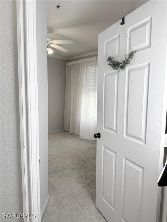 hallway featuring light colored carpet and ornamental molding