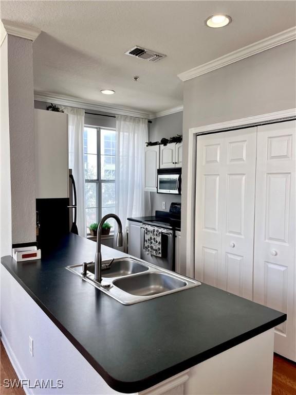 kitchen with sink, stainless steel appliances, kitchen peninsula, and white cabinets