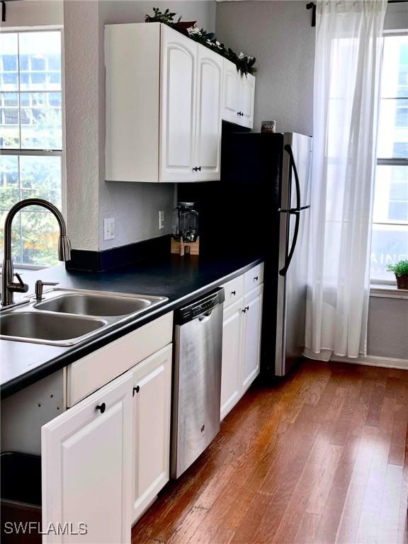 kitchen with white cabinetry, sink, stainless steel dishwasher, and dark hardwood / wood-style flooring