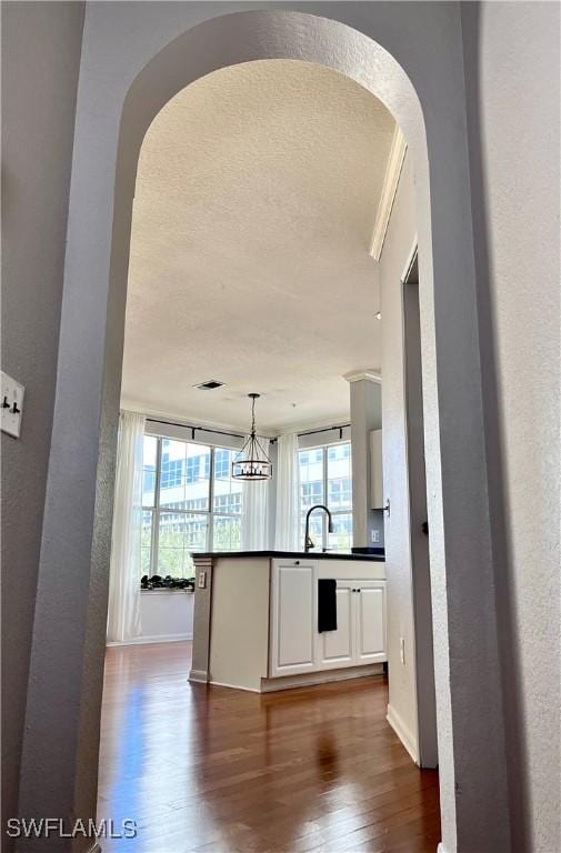 kitchen featuring hanging light fixtures, dark hardwood / wood-style floors, a wealth of natural light, and white cabinets