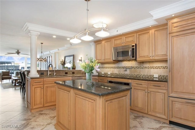 kitchen featuring sink, ornate columns, kitchen peninsula, a kitchen island, and pendant lighting