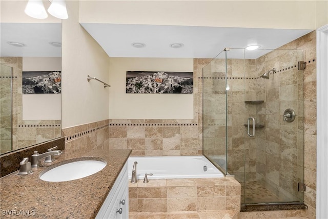 bathroom with vanity, independent shower and bath, and tile walls