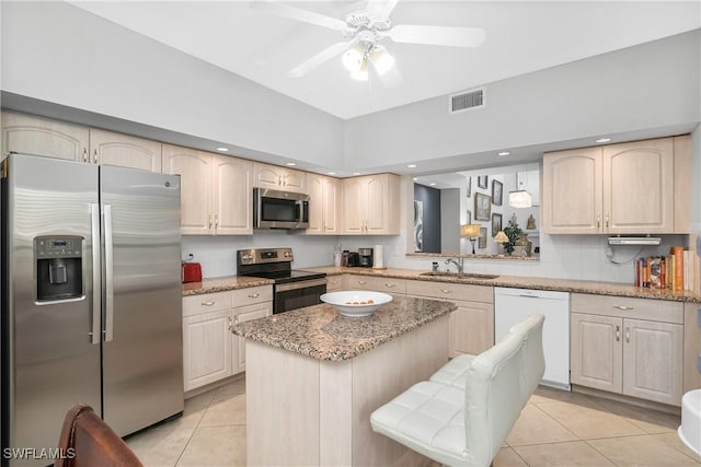 kitchen with light tile patterned floors, stainless steel appliances, sink, and light stone countertops