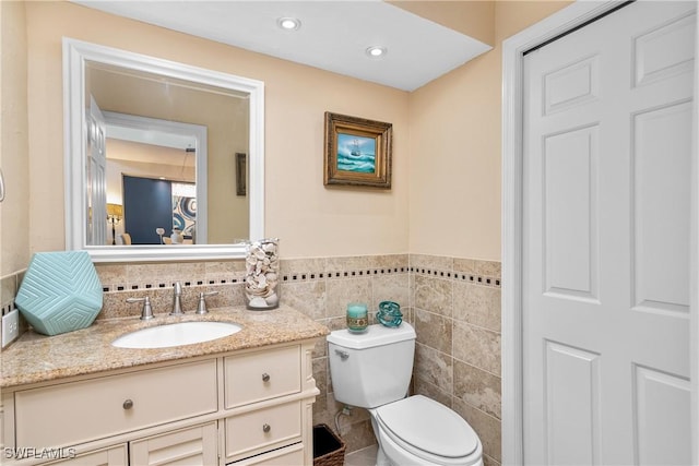 bathroom with tile walls, vanity, and toilet