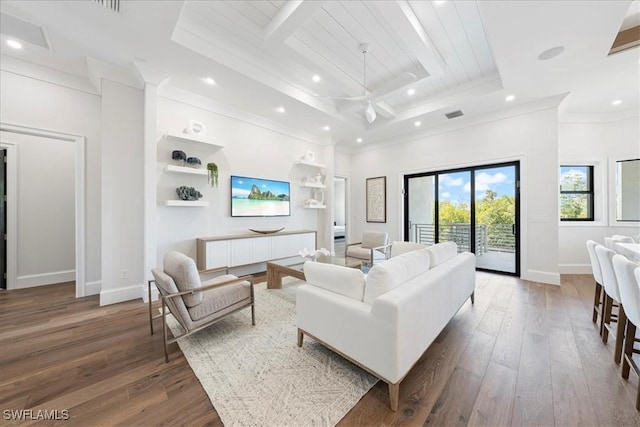 living room featuring a tray ceiling, built in shelves, dark hardwood / wood-style floors, and crown molding