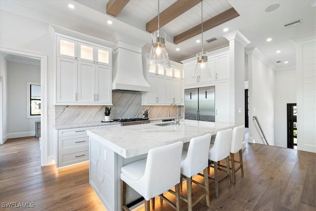 kitchen featuring premium range hood, white cabinetry, beam ceiling, and sink