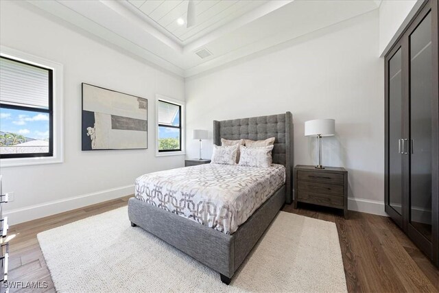 bedroom with dark hardwood / wood-style floors and a raised ceiling