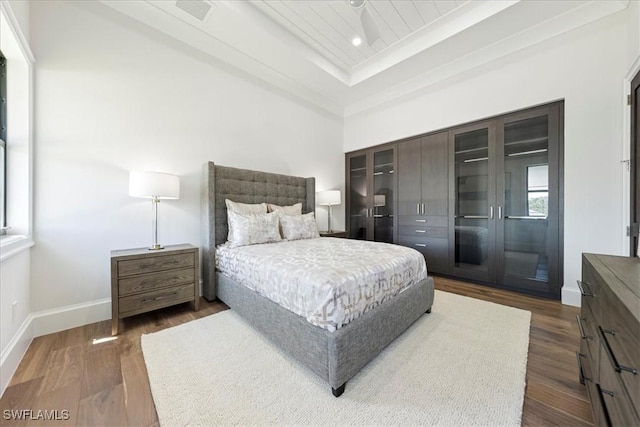 bedroom with a towering ceiling, a raised ceiling, a closet, and dark hardwood / wood-style flooring