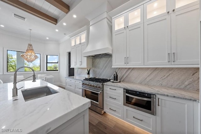 kitchen featuring white cabinets, high end range, beamed ceiling, sink, and custom range hood