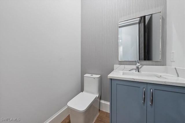 bathroom with hardwood / wood-style flooring, toilet, and vanity