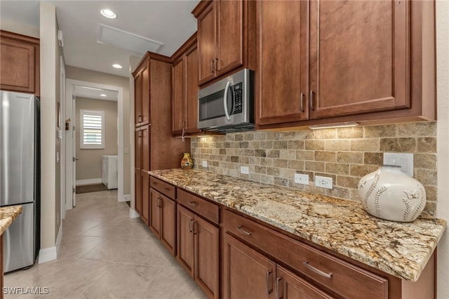 kitchen featuring light tile patterned floors, light stone countertops, backsplash, and appliances with stainless steel finishes