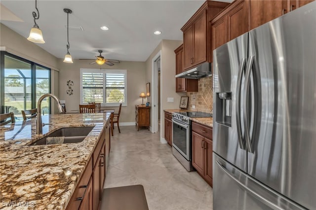 kitchen with appliances with stainless steel finishes, sink, decorative light fixtures, tasteful backsplash, and light stone counters