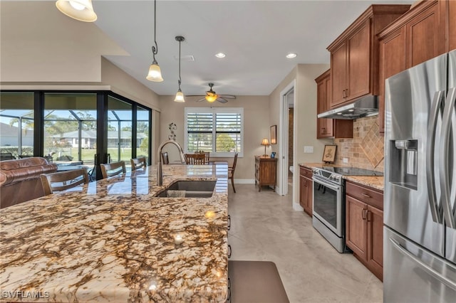 kitchen featuring light stone countertops, hanging light fixtures, decorative backsplash, sink, and stainless steel appliances