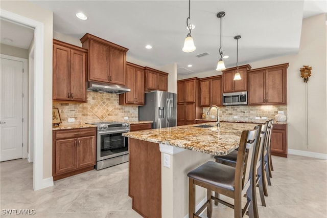 kitchen featuring a breakfast bar, sink, decorative light fixtures, an island with sink, and stainless steel appliances